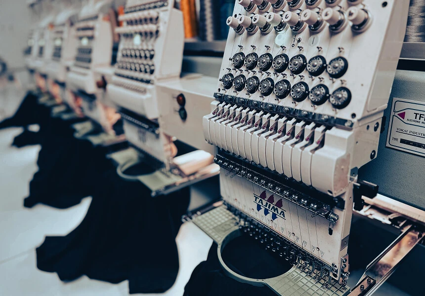 Embroidery machines stitching dark apparel in a production shop